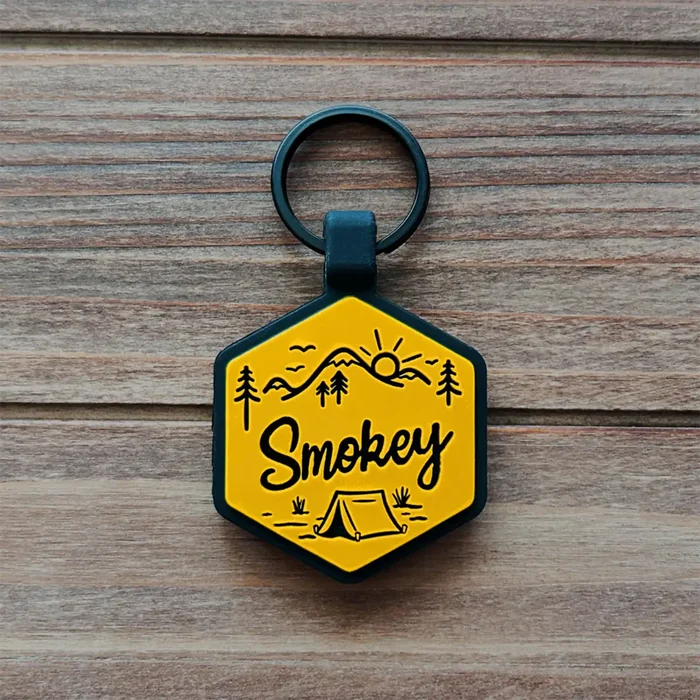 Hexagonal silicone dog ID tag with 'Smokey' text on a wooden surface