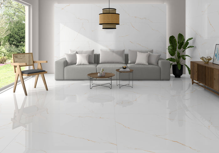 A modern living room featuring glossy white marble-look porcelain floor tiles with subtle gold veining, a light gray sofa, a wooden chair, and a large potted plant.