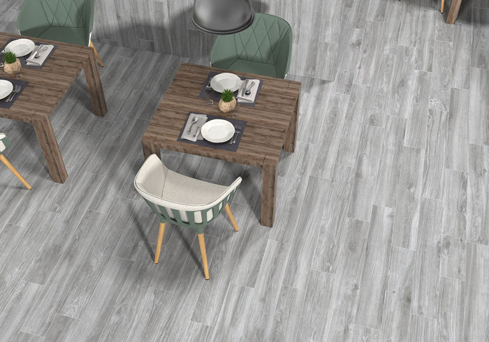 Silvery grey-washed wood look porcelain plank flooring shown installed in a room setting